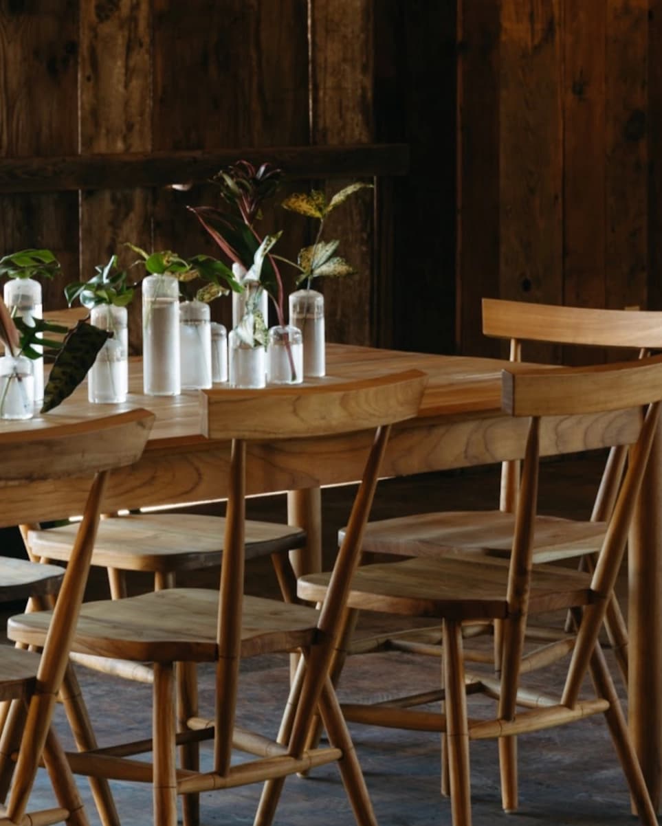 Wood tables styled with small plant arrangements in a warm interior.